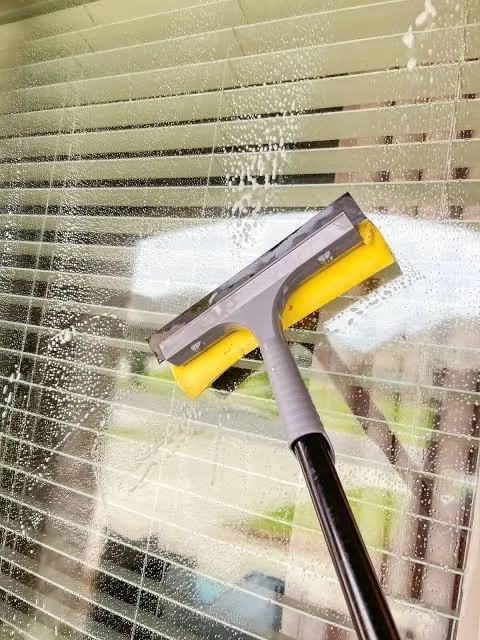 Interior window cleaned with a squeegee next to open blinds