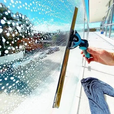 Squeegee pulling soapy water off a glass panel, finished with a microfiber cloth
