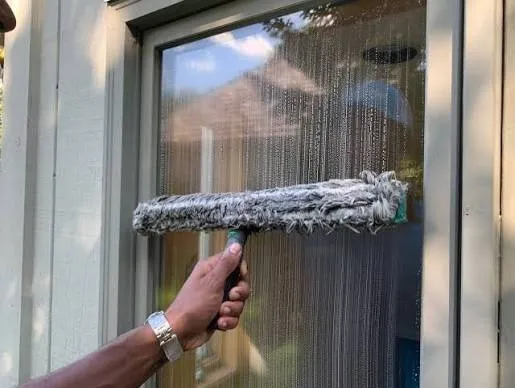 Window washer using a T-bar scrubber on a residential window in Temecula, CA