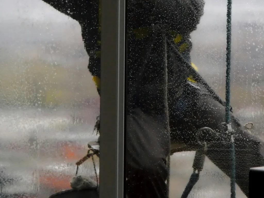 Window cleaner wiping wet exterior glass with a squeegee